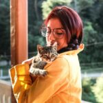 woman carrying cat while standing on porch